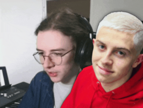 a man in a red hoodie sits next to another man in headphones