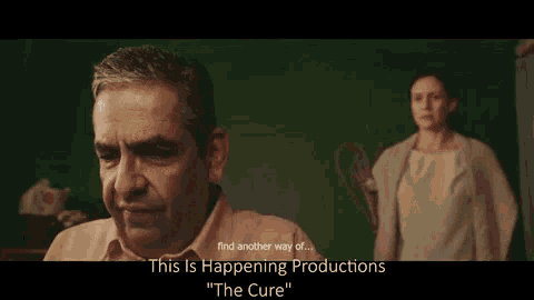 a man is crying in front of a green wall while a woman stands behind him and says this is happening productions
