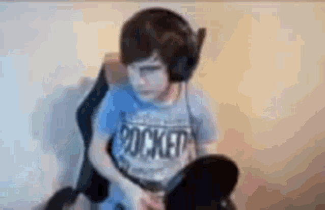 a young boy wearing headphones and a blue shirt is playing a video game .