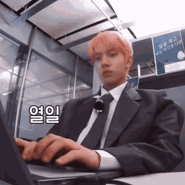 a man in a suit and tie is typing on his laptop