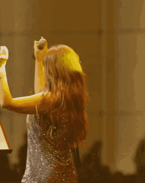 a woman is singing into a microphone while wearing a sequined dress