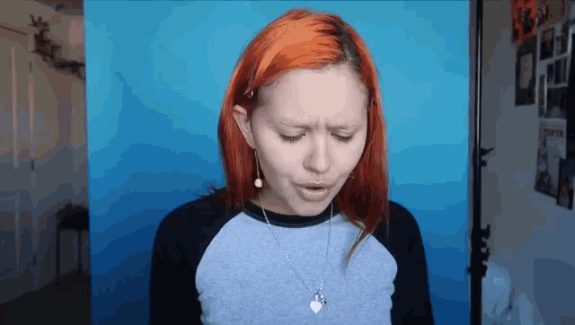 a girl with red hair and a necklace with a heart on it