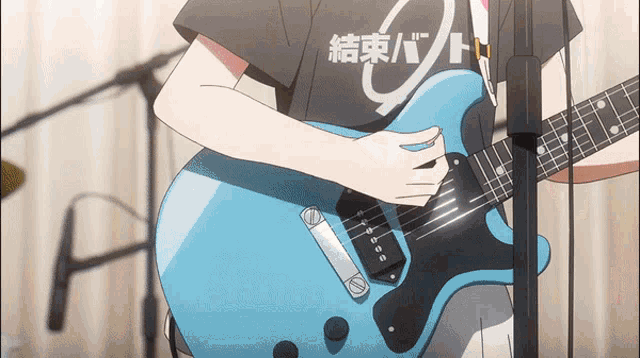 a person playing a blue guitar with a black shirt that says " 結束 バンド "