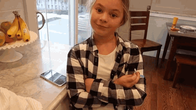 a girl in a plaid shirt is sitting at a counter
