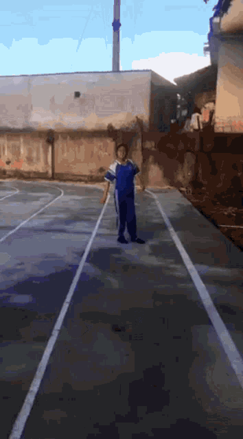 a man in a blue shirt and black pants is standing on a track
