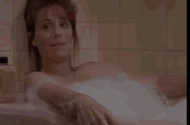 a woman is taking a bath in a bathtub full of foam .