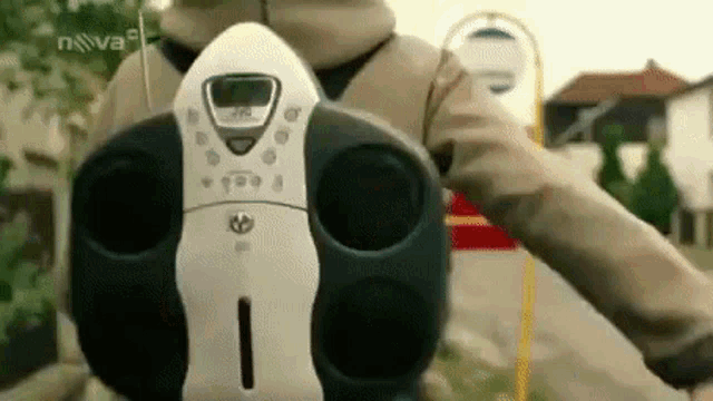 a person is holding a cd player in their hand in front of a bus stop .