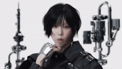a woman with short black hair is wearing a black jacket and holding a watch .