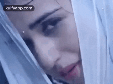 a close up of a woman 's face with a white veil covering her head .