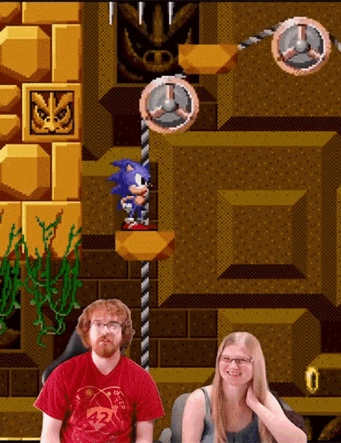a man and a woman sitting in front of a sonic the hedgehog video game