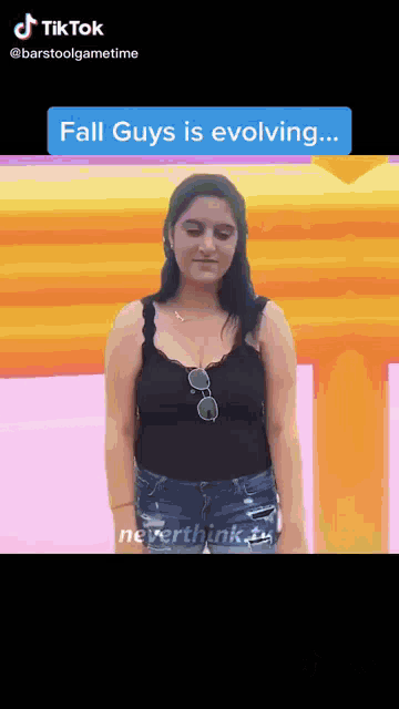 a woman in a black tank top is standing in front of a pink and yellow background with the words fall guys is evolving ..