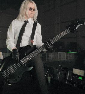 a man in a white shirt and black tie playing a bass guitar