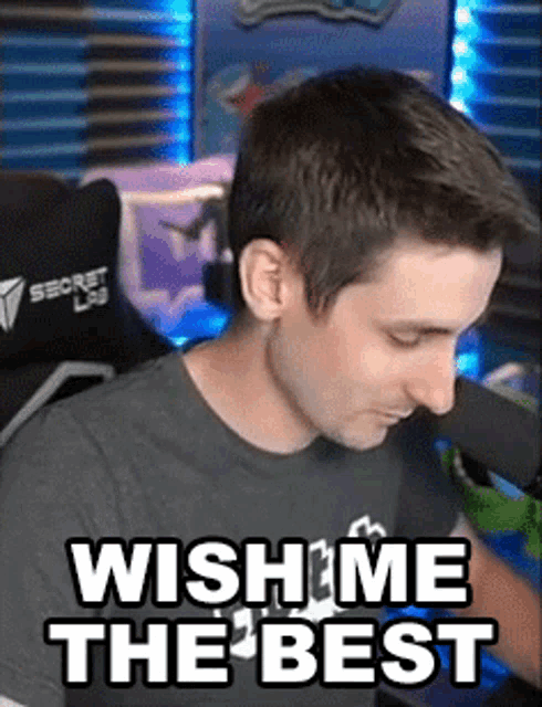 a man is sitting in front of a microphone with the words `` wish me the best '' on his face .