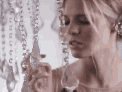 a woman is looking at a string of crystals hanging from a ceiling .
