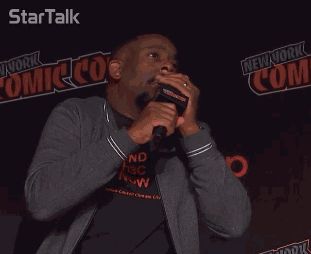 a man speaking into a microphone at a comic con