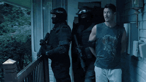 a man wearing a tank top with a skull on it is being arrested by a group of police officers