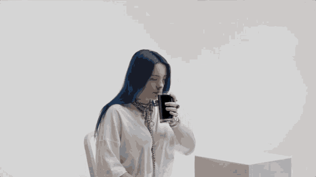 a woman with blue hair is drinking from a can