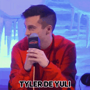 a man in a red shirt is talking into a microphone and says tyler de yulli