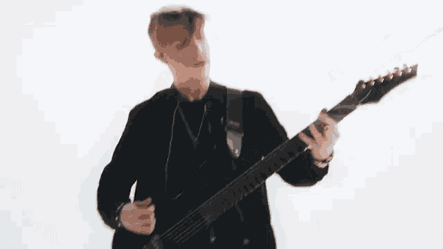 a man in a black jacket is playing a guitar .