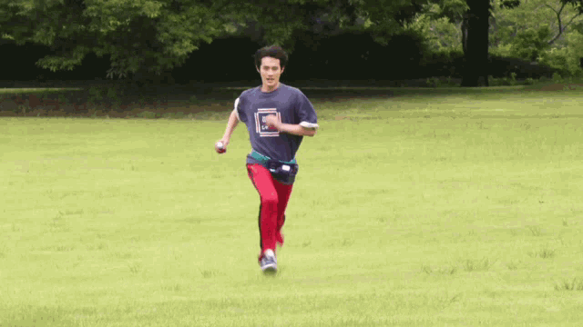 a man wearing a blue shirt with a square on it is running in a grassy field