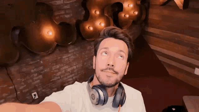 a man wearing headphones and a white shirt is taking a selfie