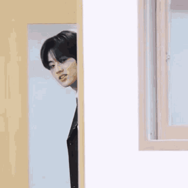 a man in a suit is peeking out from behind a door and making a funny face .