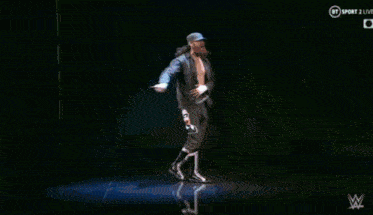 a man without a shirt is dancing on a stage in front of a screen that says bt sport