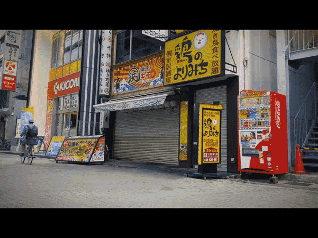 a man riding a bike in front of a store that says kicon