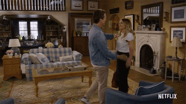a man and woman are dancing in a living room with a netflix logo on the bottom right