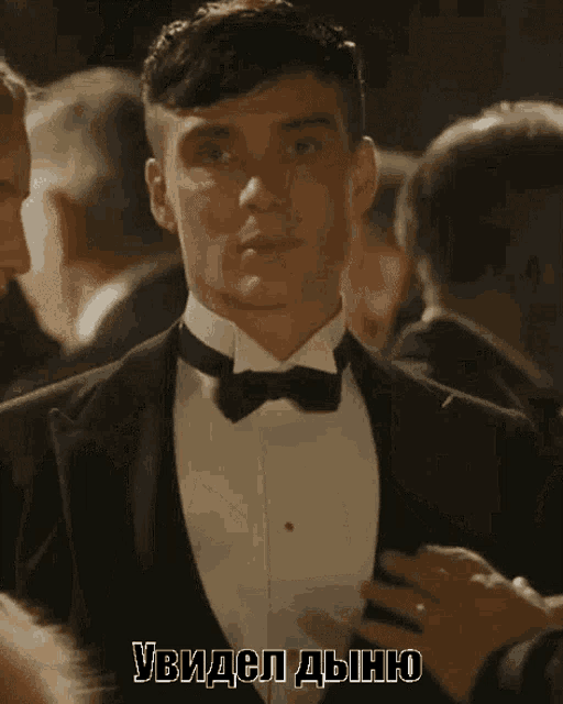 a man in a tuxedo and bow tie is being adjusted by someone with russian writing on the bottom