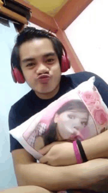 a man wearing headphones is making a funny face while holding a pillow with a picture on it .