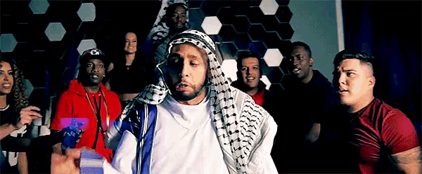 a group of people are standing around a man wearing a scarf around his head