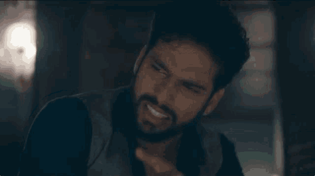 a man with a beard is smiling and making a face .