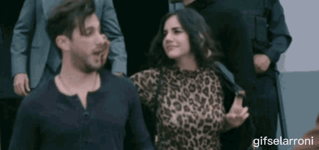 a woman in a leopard print top is being held by a man in a black shirt
