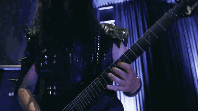 a person playing a guitar with a blue curtain in the background