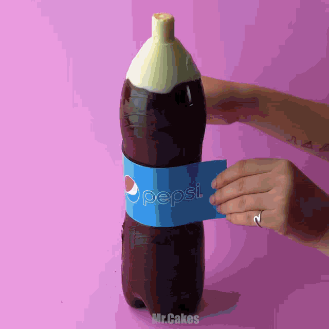 a person is holding a pepsi bottle against a pink background