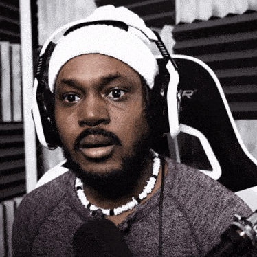 a man wearing headphones and a beanie sits in a chair that says r on it