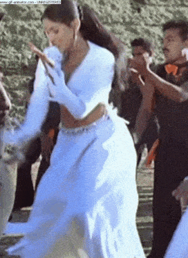 a woman in a white dress is dancing in front of a screen that says ' www.gif-animator.com ' on it