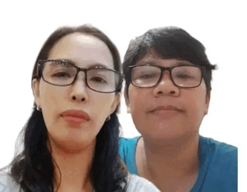 two women wearing glasses and a blue shirt are standing next to each other .