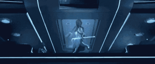 a woman in a futuristic suit is holding a light saber in a futuristic room .