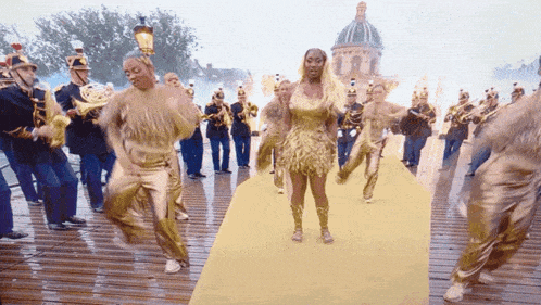 a woman in a gold dress is dancing on a yellow carpet in front of a band