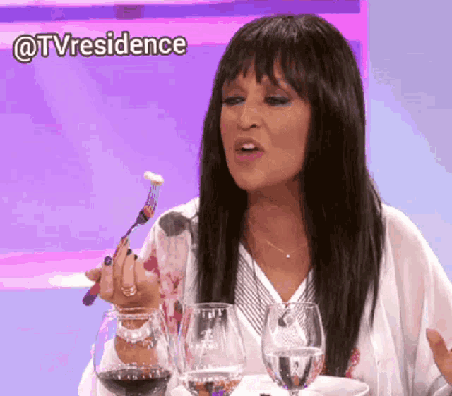 a woman sitting at a table with a glass of wine and a fork in her hand with the hashtag @tvresidence above her