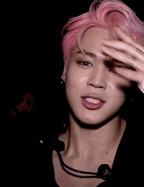 a man with pink hair is wearing a microphone around his neck