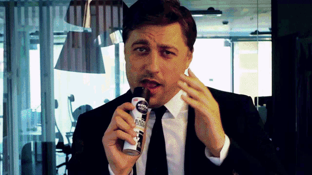a man in a suit and tie is holding a bottle of nivea men