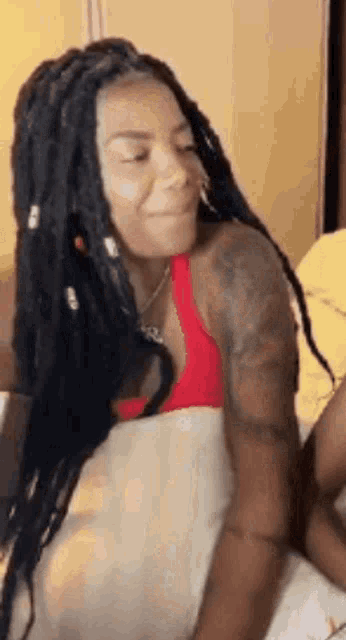 a woman with dreadlocks is sitting on a bed .