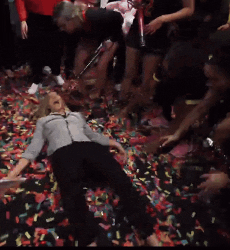 a woman laying on the floor surrounded by confetti and holding a confetti cannon