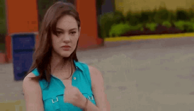 a woman in a blue tank top is giving a thumbs up .