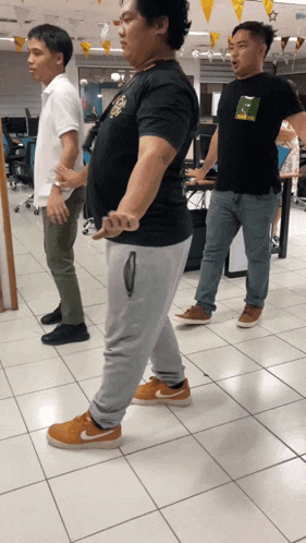 a man wearing a t-shirt that says ' abercrombie & fitch ' on it stands next to two other men