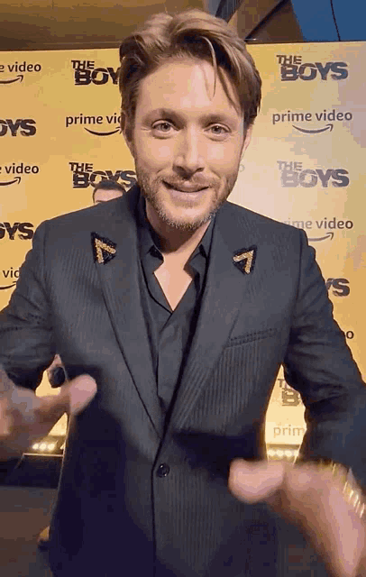 a man in a suit is standing in front of a wall that says the boys prime video