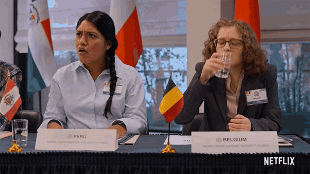two women sitting at a table with a sign that says peru